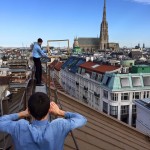 Blue-shirted social media workers scale the rooftops over Vienna with picture frame in hand