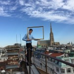 Young man holding picture frame on rooftop